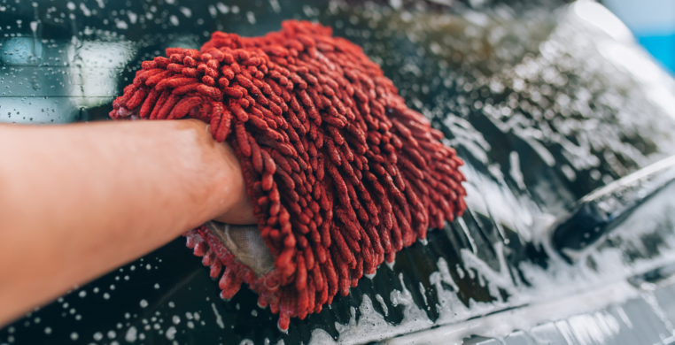 Using a high-quality, red micro-fiber wash mitt to detail a car.