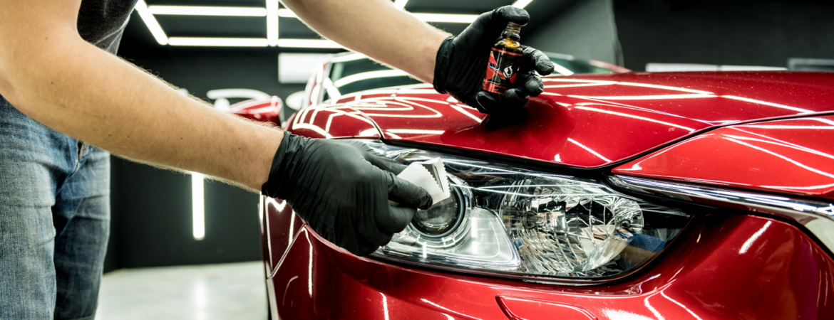 DaVinci Auto Detailing professional cleaning the headlight on a red vehicle.