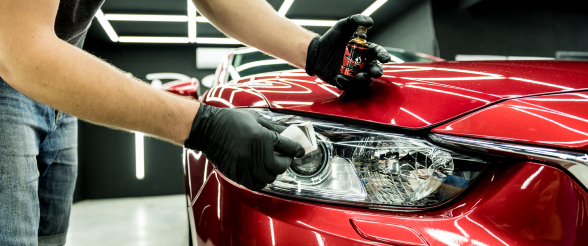DaVinci Auto Detailing professional cleaning the headlight on a red vehicle.